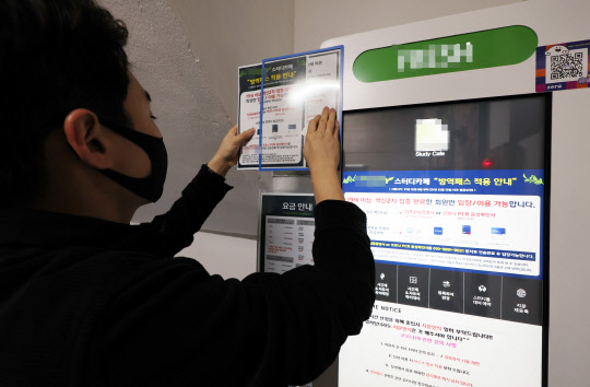 4일 오후 서울 서대문구 신촌 한 스터디카페에서 관계자가 방역패스 안내문을 제거하고 있다.  연합뉴스